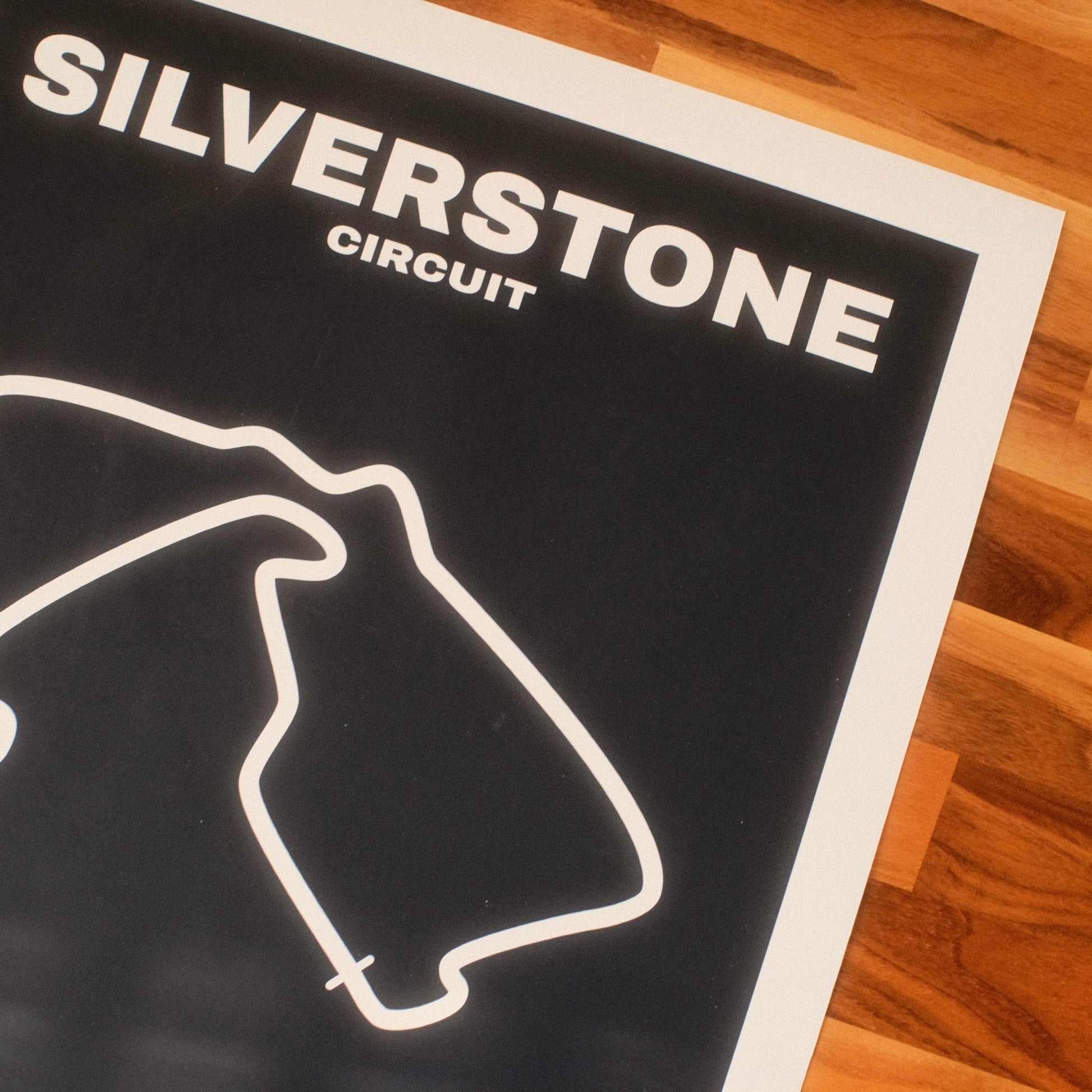 Formula 1 poster of Silverstone Circuit track and grand prix, featuring a deep navy background with a minimalist white outline of the historic Formula 1 track layout. Midcentury modern/minimal vibe.