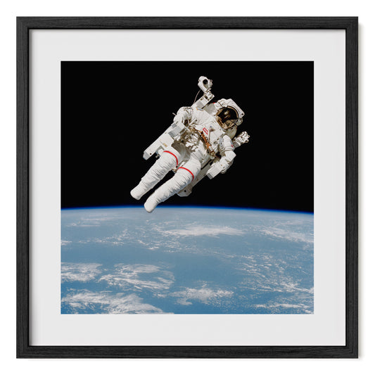 High-resolution fine art print of NASA astronaut Bruce McCandless during a 1984 spacewalk, piloting the Manned Maneuvering Unit (MMU) in space. Photography print framed in oak and tempered glass. Fine art photo print by Airdusk.