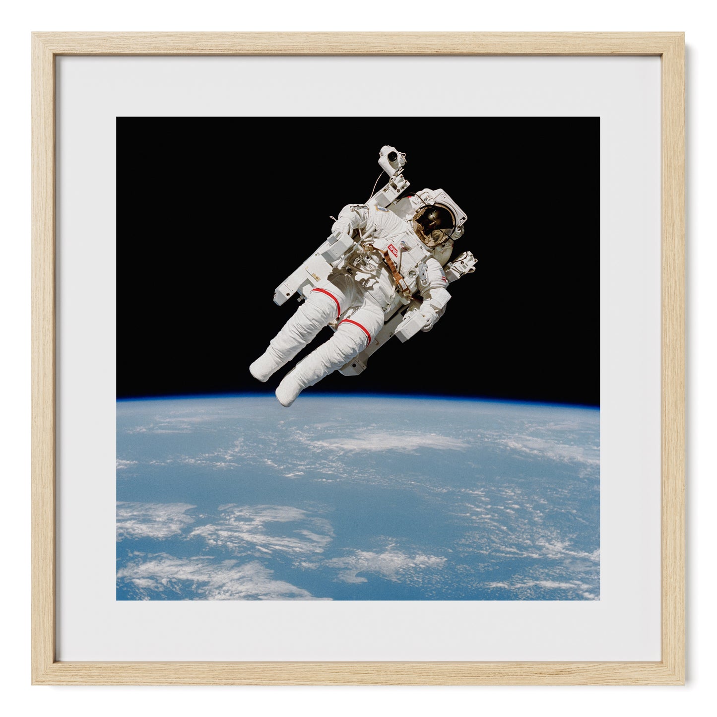 High-resolution fine art print of NASA astronaut Bruce McCandless during a 1984 spacewalk, piloting the Manned Maneuvering Unit (MMU) in space. Photography print framed in oak and tempered glass. Fine art photo print by Airdusk.